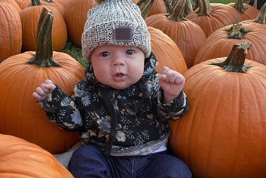 A cute baby sitting among pumpkins