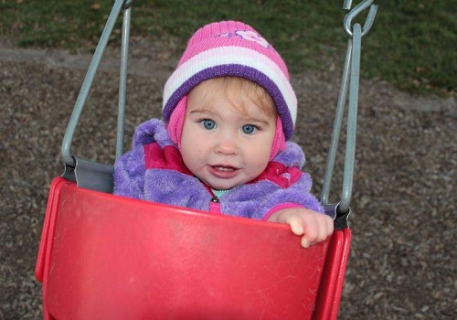 A baby peers over a swing at Tanner's Orchard, which provides an apple orchard Dunlap IL families adore.