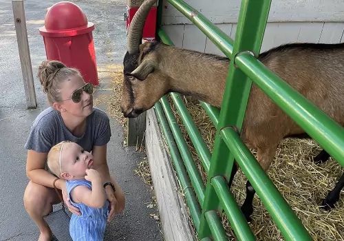 A mother and her baby look at a goat at Tanners Orchard, which offers Birthday Parties Near Bloomington IL