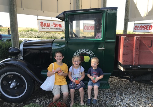 Kids pose by a truck at Tanners Orchard, which provides Apple Picking in Illinois