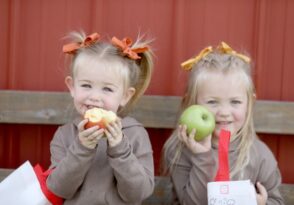 Happy little girls eating freshly picked apples at Tanners Orchard